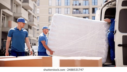 Professional Moving Services: Young Movers Transport Mattress for Delivery in Proud Workers Uniform on Company's Busy Day.