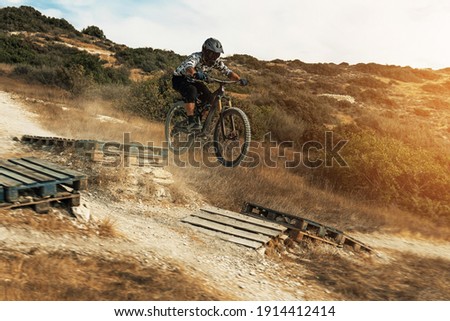 Professional MTB bike rider jumping during downhill ride on his bicycle in mountains