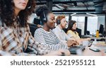 Professional multi-ethnic managers working in call center office. People sitting in row at desk and using computers. Discussing something with customers on headset. Team of workers answering calls.