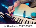 Professional Musician with condenser microphone and tablet for Mixing Mastering music. Music composer woman composing a song with guitar and piano keyboard at digital Recording home studio neon light