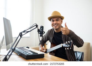 Professional Musician With Condenser Microphone And Tablet For Mixing Mastering Music. Hispanic Male Composing A Song With Guitar And Piano Keyboard At Digital Recording Home Studio