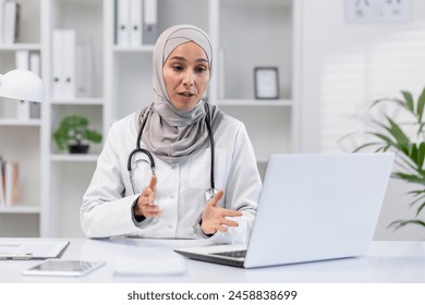 A professional Muslim female doctor in a hijab explaining healthcare options, seated at her desk in a bright, modern clinic office. She looks engaged and knowledgeable. - Powered by Shutterstock