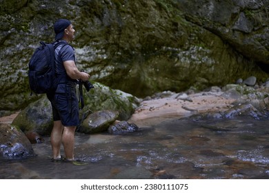 Professional nature photographer with backpack taking shots in a gorge - Powered by Shutterstock