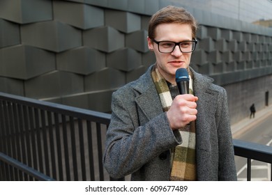 Professional News Reporter In Eyeglasses With Microphone Broadcasting On The Street Professional News Reporter In Eyeglasses With Microphone Broadcasting On The Street