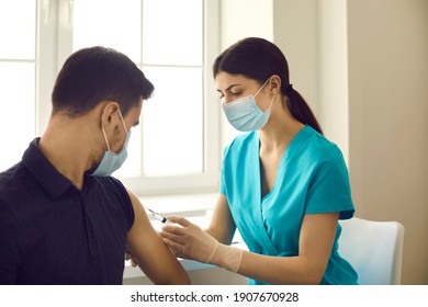 Professional nurse or doctor injects a patient with a flu or coronavirus vaccine in a modern clinic. Male patient receives an annual mandatory vaccination. Concept of prevention of viral diseases.