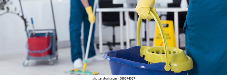 Professional office cleaner is holding a bucket