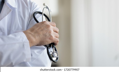 Professional older mature male doctor physician or cardiologist wearing white uniform holding stethoscope in hand. Cardiology medical clinic, cardiac treatment concept. Close up view, copy space.