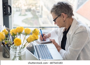 Professional Older Woman Working At Desk With Computer By A Window (selective Focus)