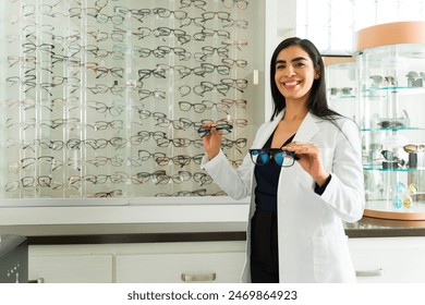 Professional ophthalmologist holding spectacles, ready to assist a patient in selecting eyewear at a modern optician's clinic - Powered by Shutterstock