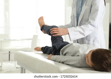 Professional orthopedist examining little patient's leg in clinic - Powered by Shutterstock