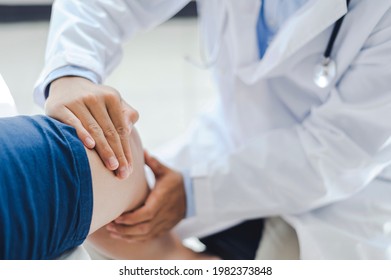 Professional orthopedist examining the little patient's leg in the clinic. Patient at the physiotherapy doing physical exercises with his therapist - Shutterstock ID 1982373848