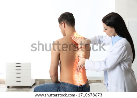 Professional orthopedist examining man in medical office. Spinal pain