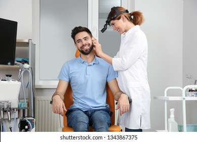 Professional otolaryngologist examining man in clinic. Hearing disorder