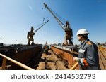 Professional overseeing extensive shipbuilding process, massive cranes erect vessel in dry dock against a clear sky. Maritime engineer in hardhat and reflective vest monitors construction.