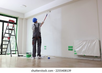 Professional painter paints office wall with roller brush. Decoration and improvement office interior concept.
