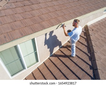 Professional Painter Using A Brush to Paint House Fascia.