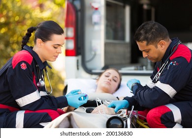 professional paramedics giving unconscious young woman first aid