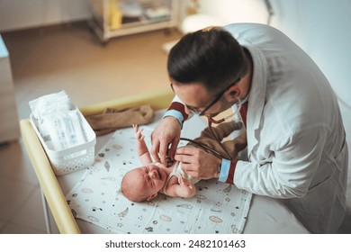 A professional pediatrician in medical attire gently examines a newborn baby lying on a hospital changing table, using a stethoscope for health assessment. - Powered by Shutterstock