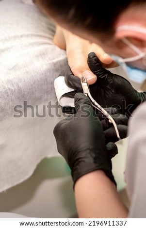 Professional pedicure. Pedicure master wearing latex gloves cuts female toenails in the beauty salon, closeup