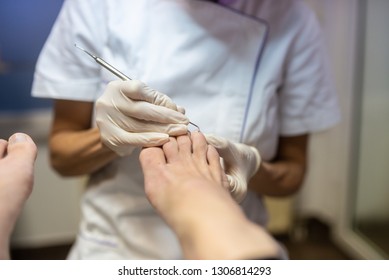 Professional pedicurist removing cuticle with stainless steel tool from a toe nail in a cosmetics salon. - Shutterstock ID 1306814293