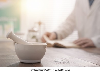 Professional pharmacist grinding a medical preparation using a mortar and pestle, pharmacy and medicine concept, hands close up