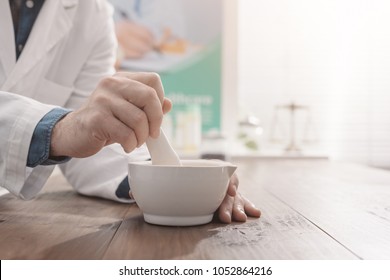 Professional pharmacist grinding a medical preparation using a mortar and pestle, pharmacy and medicine concept, hands close up