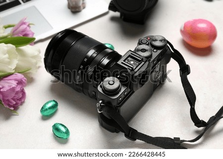 Professional photo camera, tulips and Easter eggs on white background, closeup