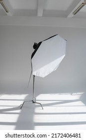 Professional photo flash light with a octbox on a c-stand on a cyclorama in modern photo studio with a huge windows. Professional lighting equipment, flashes, c-stands.