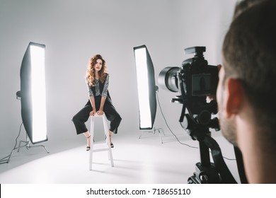 professional photographer and beautiful model on fashion shoot in photo studio with lighting equipment  