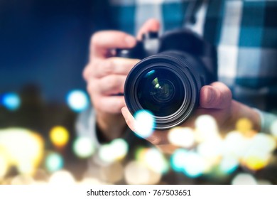 Professional photographer with camera. Man taking photos late at night. Photography and paparazzi concept. Abstract bokeh city lights.