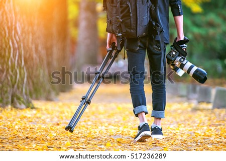 professional photographer with camera and tripod in autumn.