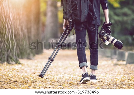 professional photographer with camera and tripod in autumn. Vintage tone.