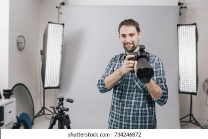 Professional photographer posing in the studio and holding a digital camera, he is ready for the photo shoot - Powered by Shutterstock