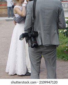 Professional Photographer Resting Before Taking Photo Of Wedding Couple. Just Married Bride And Groom Embracing And Dancing. No Faces.