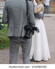 Professional Photographer Resting Before Taking Photo Of Wedding Couple. Just Married Bride And Groom Embracing And Dancing. No Faces.