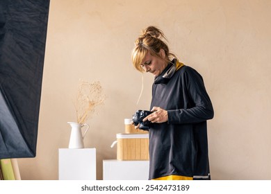 Professional photographer reviewing captured images on her digital camera in a contemporary studio setting - Powered by Shutterstock