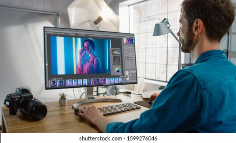 Professional Photographer Sitting at His Desk Uses Desktop Computer in a Photo Studio Retouches. After Photoshoot He Retouches Photographs of Beautiful Female Model in an Image Editing Software