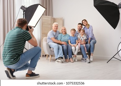 Professional photographer taking photo of family on sofa in studio