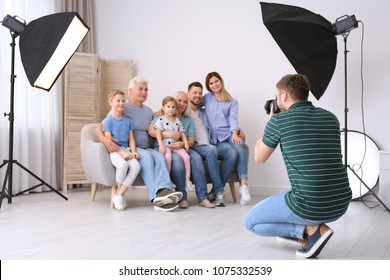 Professional Photographer Taking Photo Of Family On Sofa In Studio