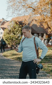 Professional Photographer Taking Picture Of Beautiful Autumn Park. Man Professional Photographer standing With Camera And With Smartphone In Autumn Park. Retouched, Vibrant Colors