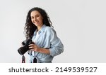 Professional Photographer Woman Holding Photo Camera Posing Smiling To Camera Standing Over White Wall Background. Lady Taking Photos Posing With Photocamera. Photography. Free Space For Text