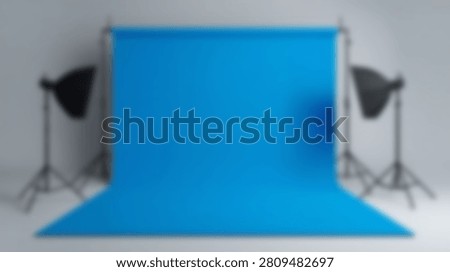 A professional photography studio setup featuring a vibrant blue backdrop and two studio lights on stands, ready for a photoshoot.