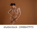 Professional photoshoot. Woman with slim body shape is posing against background.