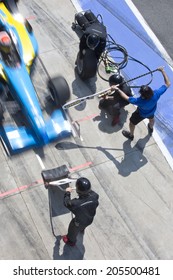 Professional Pit Crew Ready For Action As Their Team's Race Car Arrives In The Pit Lane During A Pitsstop Of A Car Race, Concept Of Ultimate Teamwork