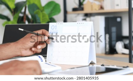 Professional planning monthly schedule using a desk calendar and notebook in a modern office, representing time management, business planning, appointment scheduling, productivity, organization, and workflow efficiency.