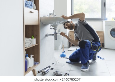 Professional plumber checking drain pipes at home and using pliers - Powered by Shutterstock