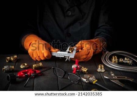 Professional plumber measures the diameter of a fitting with a caliper. Working environment in the workshop during connection of the gas installation