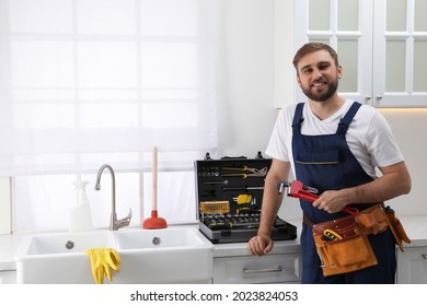 Plumero profesional con émbolo e instrumentos cerca del fregadero en la cocina