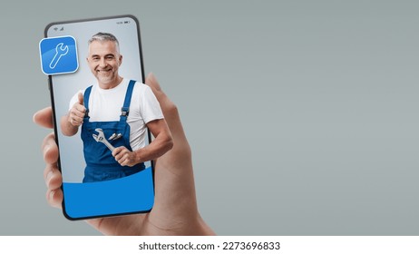 Professional plumber and repairman on smartphone screen: hire contractors online - Powered by Shutterstock