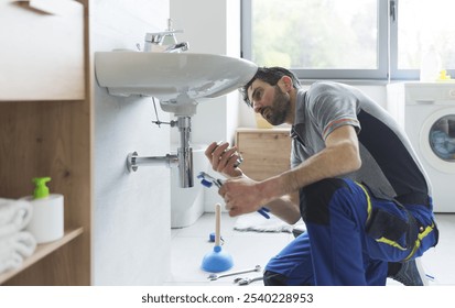 Professional plumber working on a bathroom sink and replacing parts